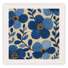 Firkantet broderi med blå og orange blomsterdesign på beige stofbaggrund.