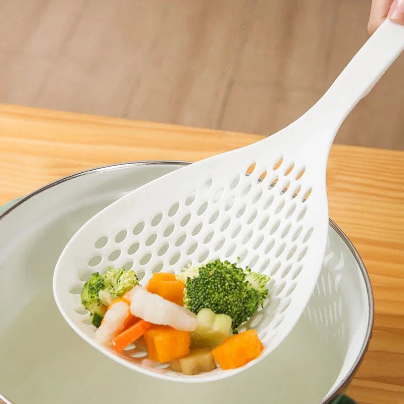 A white long-handled kitchen strainer spoon is shown resting on a plate filled with chopped vegetables.