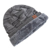 A gray knit beanie with a folded cuff and a fluffy gray faux fur trim.