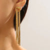 Gold geometric tassel drop earrings hanging from an ear