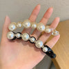 يد تحمل مجموعة من مشابك الشعر الأنيقة المرصعة بأحجار الراين واللؤلؤ للنساء.