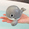 A gray suction cup bath basketball hoop with three balls is held in a person's hand.