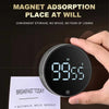 A hand holds a magnetic kitchen timer displaying 99:55, next to a note listing breakfast items.