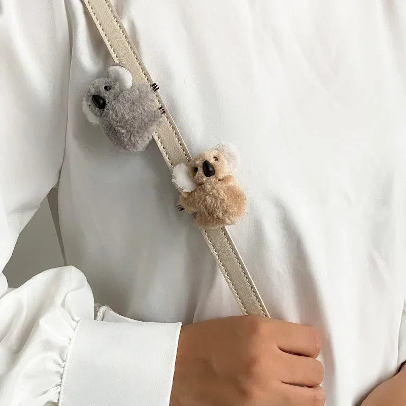 يد تحمل مقطع شعر بيج مع حيوان كوالا رمادي ناعم.