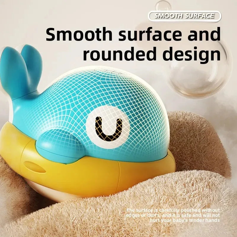 A blue and yellow musical light-up whale baby bath toy with a smooth, rounded design resting on a soft, brown surface.