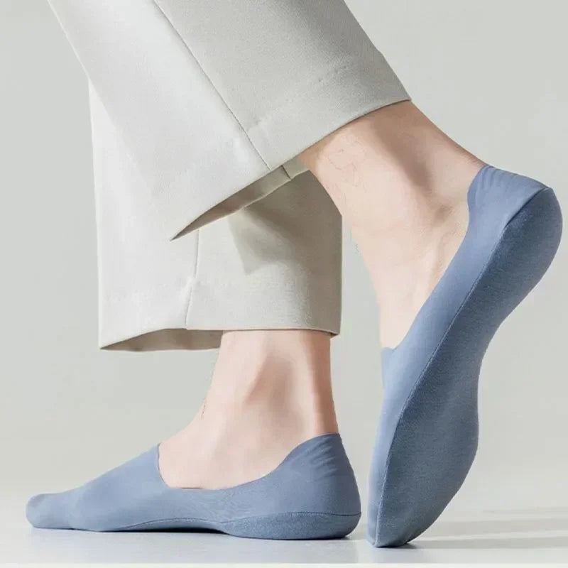 A close-up of a light blue silicone grip insoles for shoes, shown next to a person's foot.