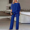 En kvinne modellerer et kongeblått to-delt sett med en off-shoulder topp med gjennomsiktige ermer og brede buksebein.