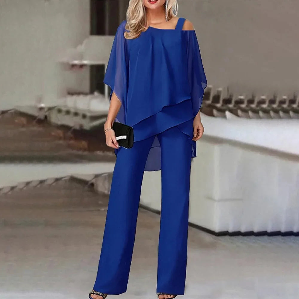 En kvinne modellerer et kongeblått to-delt sett med en off-shoulder topp med gjennomsiktige ermer og brede buksebein.
