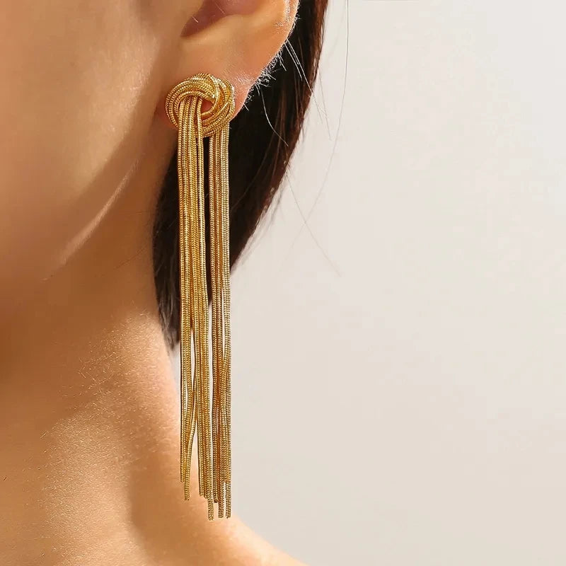 Gold geometric tassel drop earrings hanging from an ear