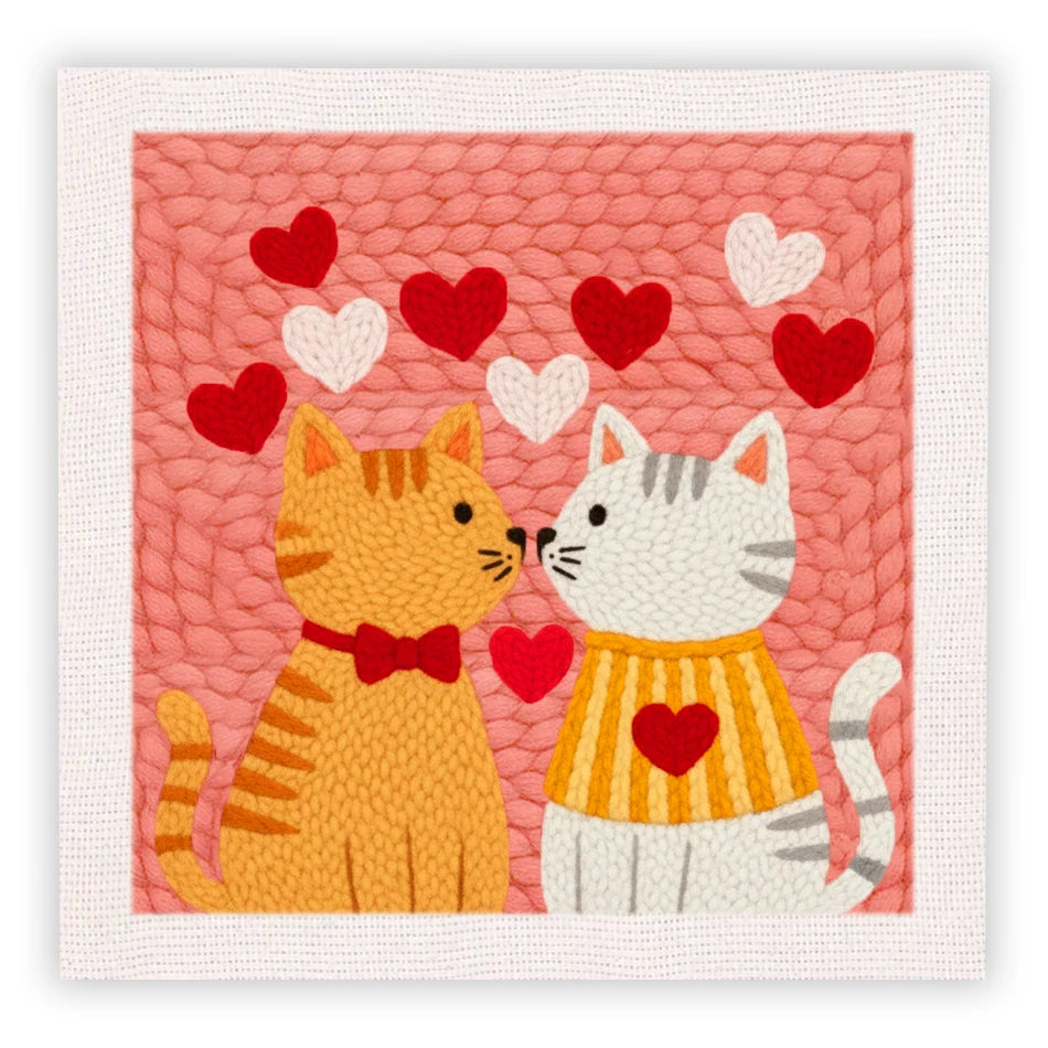 Kit de bordado de punch needle con un gato atigrado amarillo y un gato blanco sobre fondo rosa con corazones rojos y blancos.