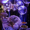 A display of blue LED light-up balloons with pre-strung lights hanging against a dark blue backdrop.
