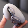 A hand holds a white breathable baby first walker shoe with a gray textured insert.