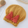 Gorro de microfibra color marrón dorado con un lazo color melón sobre una superficie blanca.