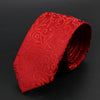 Corbata roja vibrante de jacquard con patrón de volutas ornamentadas, doblada sobre un fondo oscuro.