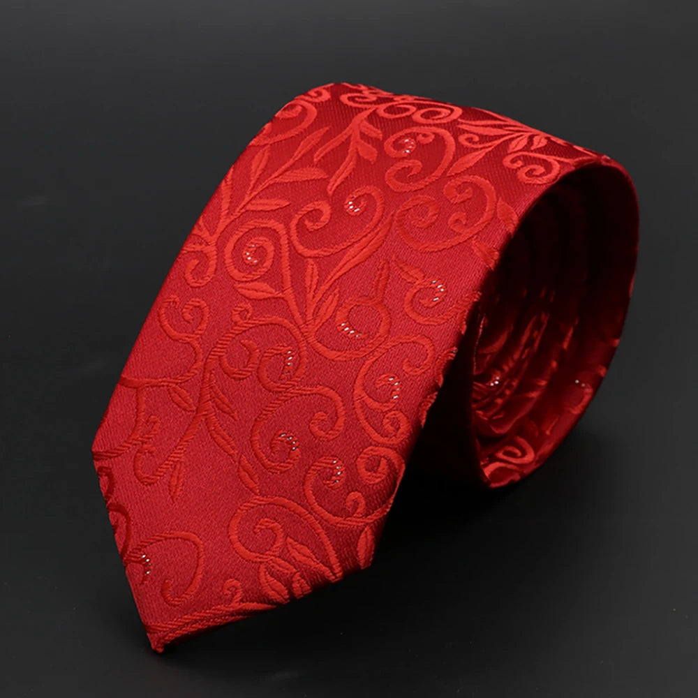 Corbata roja vibrante de jacquard con patrón de volutas ornamentadas, doblada sobre un fondo oscuro.