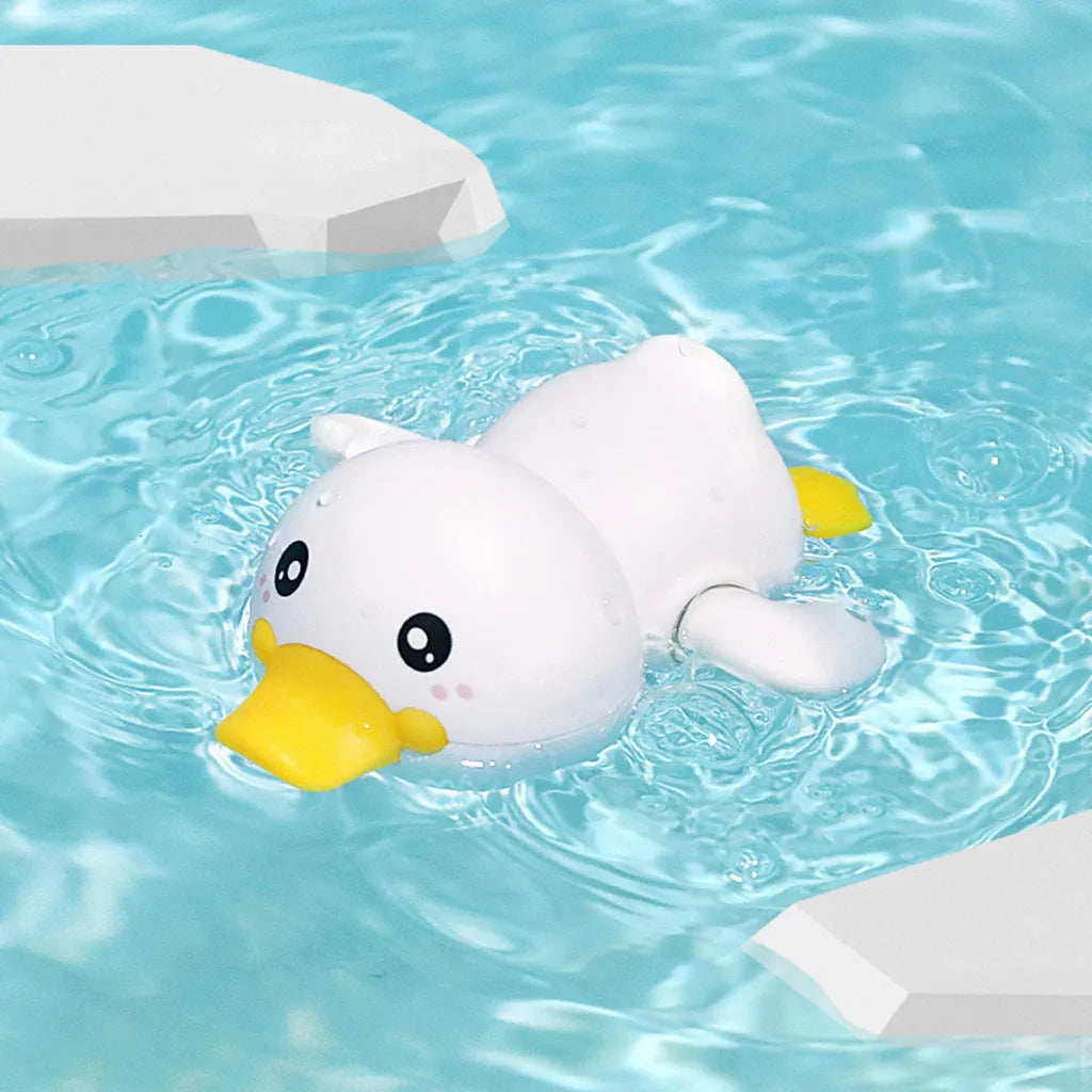 A white duck bath toy floating in clear blue water with white blocks nearby.