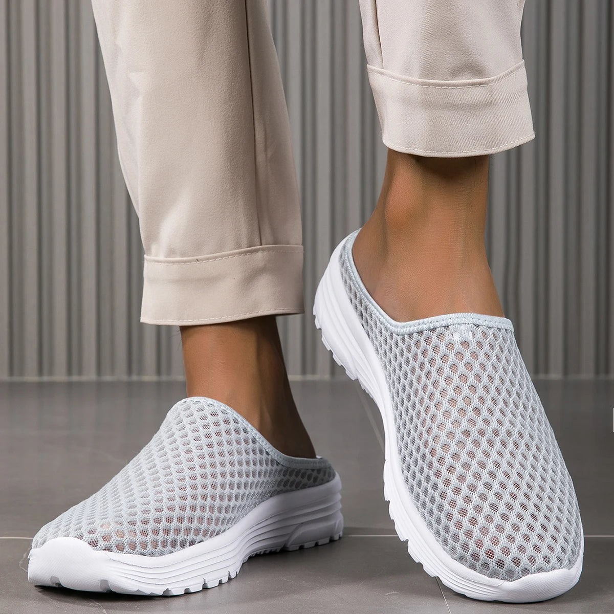 A pair of light beige breathable mesh slide sandals with white non-slip EVA outsoles being worn by a person.