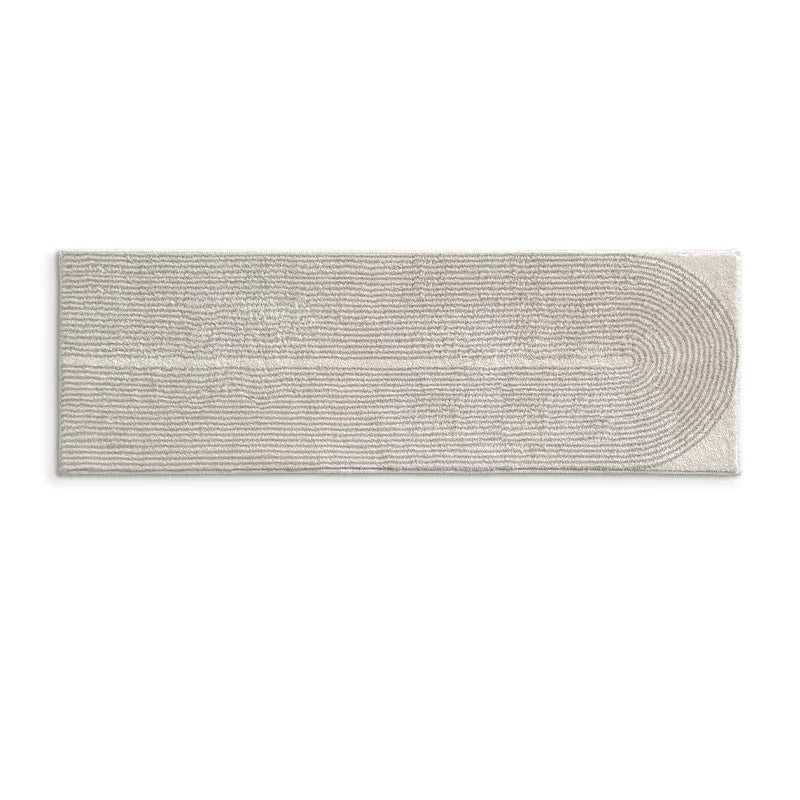 A rectangular cozy rug with horizontal lines and a curved design in a light beige color.