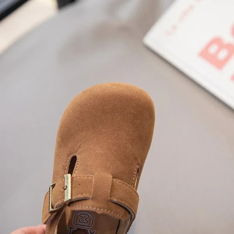 A close-up of a brown retro non-slip kids' moccasin shoe with an easy hook-and-loop closure.