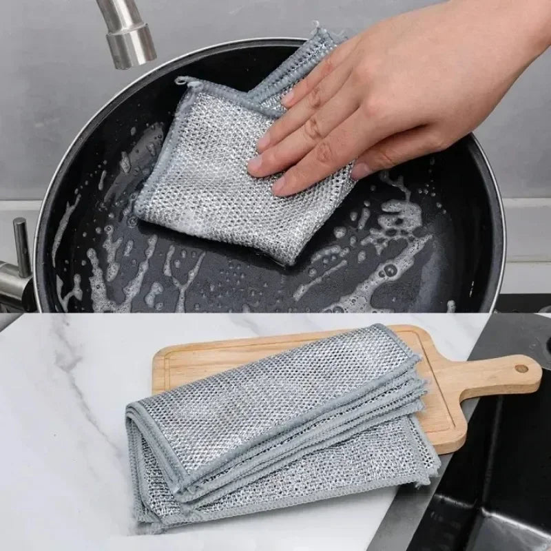 A hand is placing a stack of gray scratch-free microfiber cleaning cloths into a black frying pan.