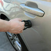 Une main utilise un extracteur de bosses à ventouse noire sur le panneau de porte d'une voiture de couleur claire.