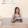 A woman is relaxing on a sofa with a cup of tea, next to a portable USB heated blanket displaying temperature settings.