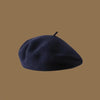 A dark navy blue wool beret hat resting on a plain brown background.
