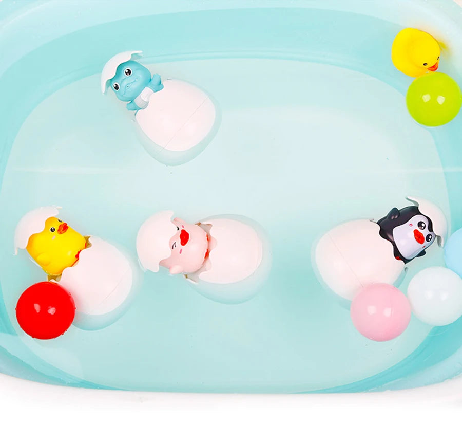 A set of cute duck and penguin bath toys with water spray fun floating in clear blue water.