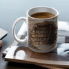Hvit keramikk kaffekopp med design av gammel, slitt bokhylle og karttekstur.