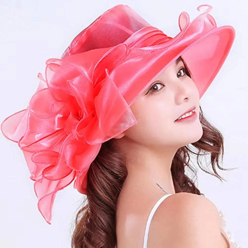 A woman wearing a vibrant pink wide brim sun hat made of organza with ruffled mesh details.