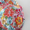 A close-up of a baby girl's floral print dress and matching hat with colorful flowers.