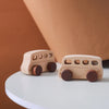 A light wood hand-pushed cart toy for toddlers resting on a white surface.