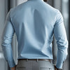 A man wearing a light blue long-sleeve formal shirt and gray trousers, viewed from the back.
