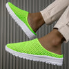 A close-up of bright lime green breathable slide sandals with a white non-slip EVA outsole on a person's foot.
