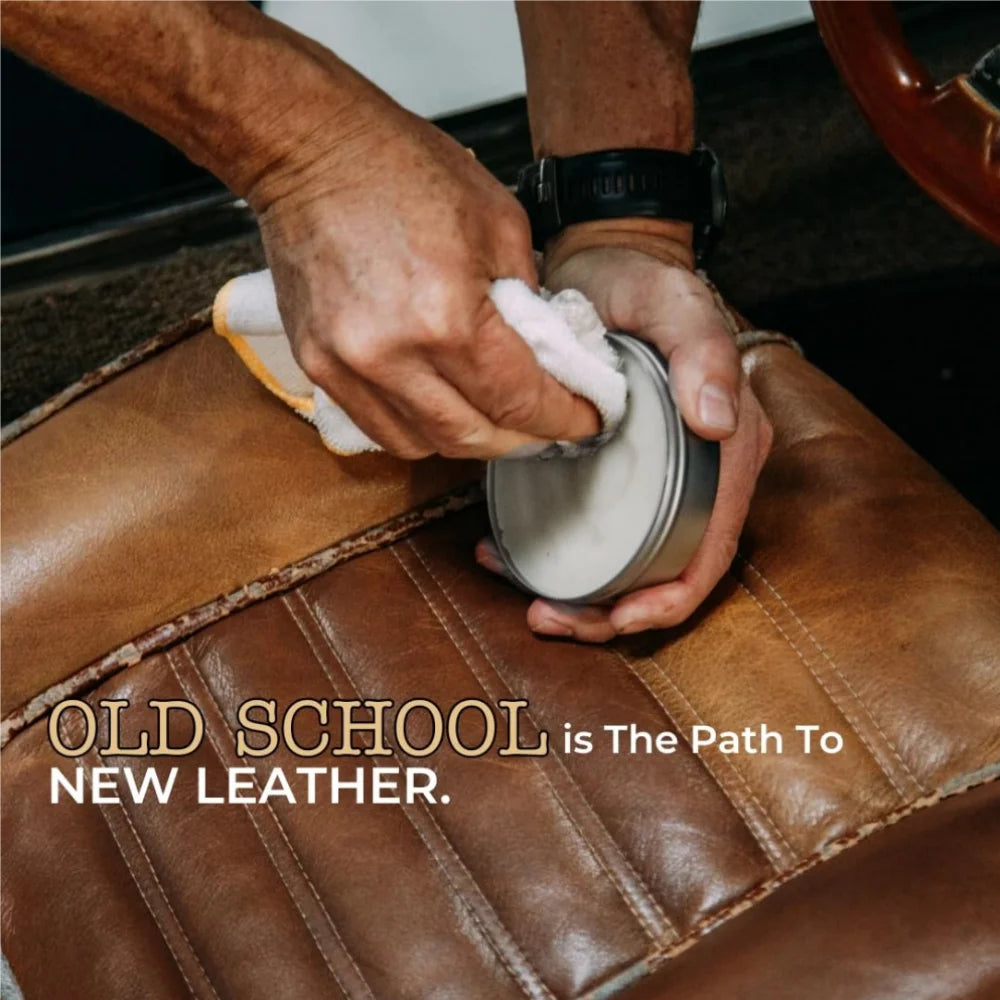 Hands are applying clear leather conditioner balm to brown leather upholstery.