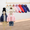 A display of various colored kids hooded puffer jackets hanging on a wooden rack.