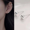Silver geometric tassel drop earrings displayed next to a person's ear.