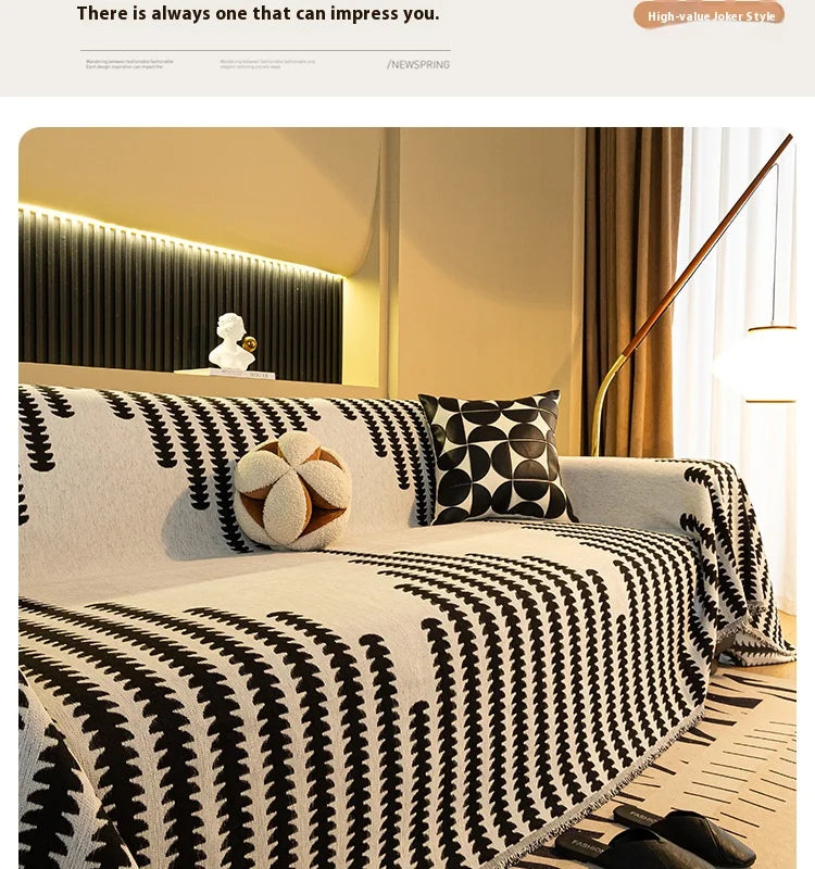 A black and white striped chenille sofa blanket draped over a light-colored sofa in a modern living room.