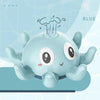 A light blue musical whale bath toy with fins and a water spray coming from its head.