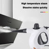 A white handheld steam cleaner is shown emitting high-temperature steam onto a dark appliance to dissolve stains quickly.