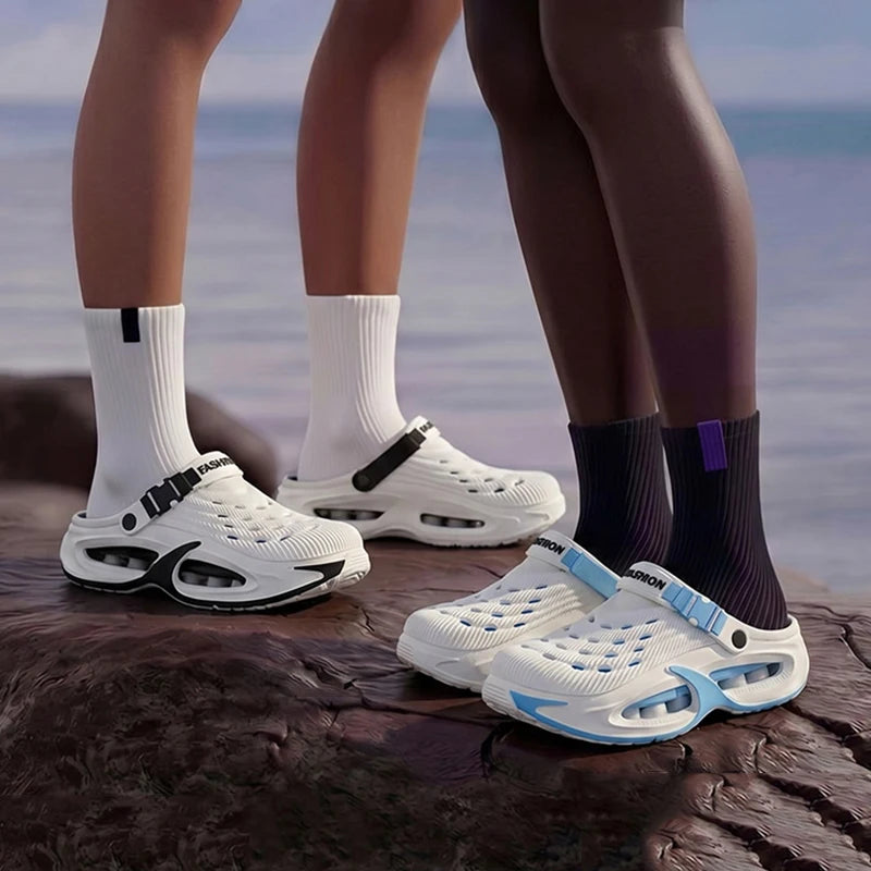 A pair of white and blue EVA slip-on sandals are shown resting on a dark, textured surface next to a person's legs.