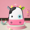 A pink and white cartoon cow-themed backpack with yellow accents sitting on a light pink stand.