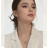 A close-up of a woman wearing a dainty gold heart pendant necklace with a snake chain.
