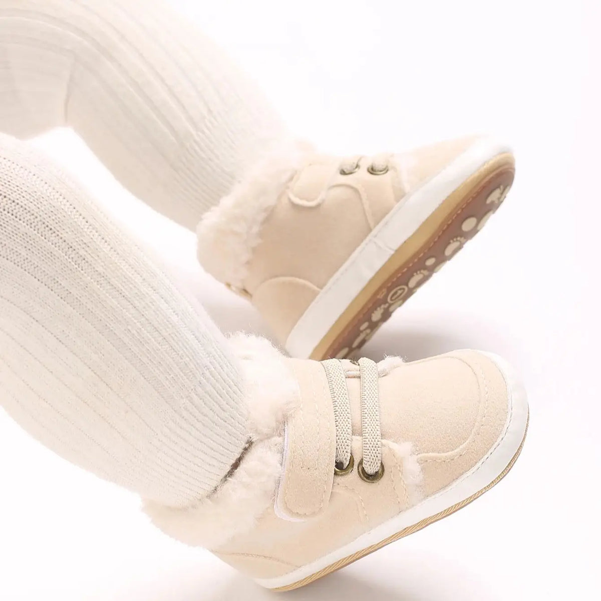 A pair of beige soft cotton baby winter snow boots with faux fur trim and white socks.