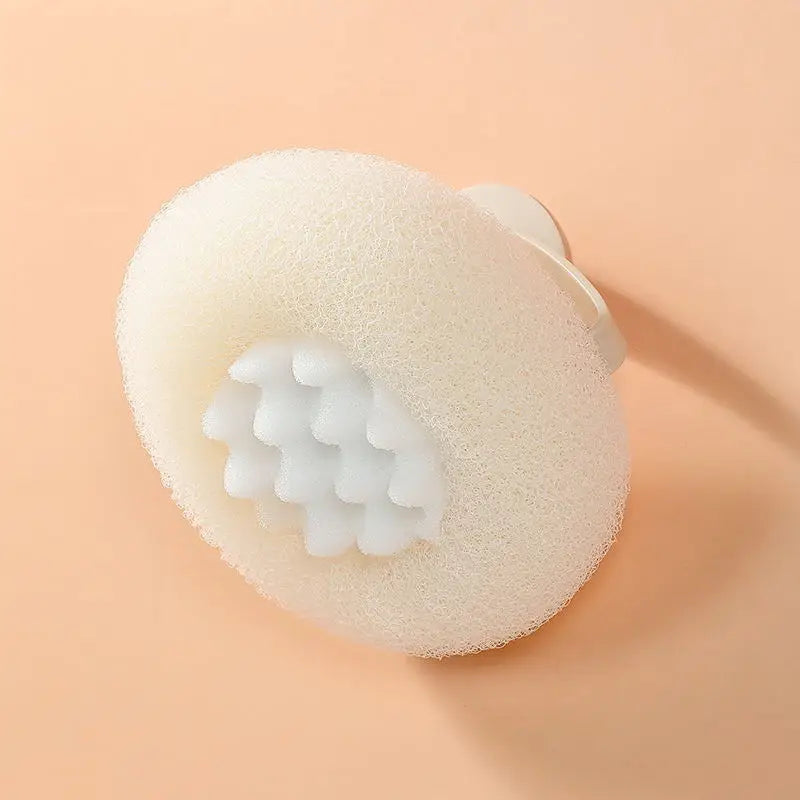 A round, light beige bath sponge with a suction cup attachment is shown against a neutral background.