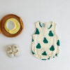 A white cotton sleeveless bodysuit with a green fruit pattern, next to a woven plate and a pair of baby shoes.
