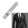 A silver metal tie clip shown next to a man wearing a black suit and tie.