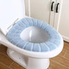 A white toilet with a light blue, textured acrylic seat cover installed.