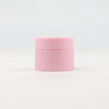 A pink refillable travel face cream jar with a leak-proof lid.