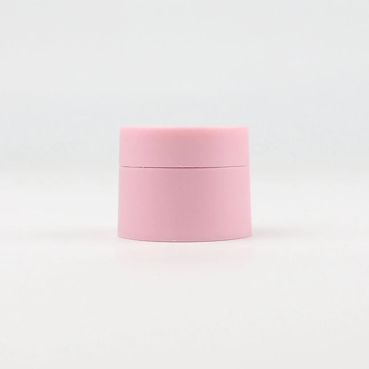 A pink refillable travel face cream jar with a leak-proof lid.